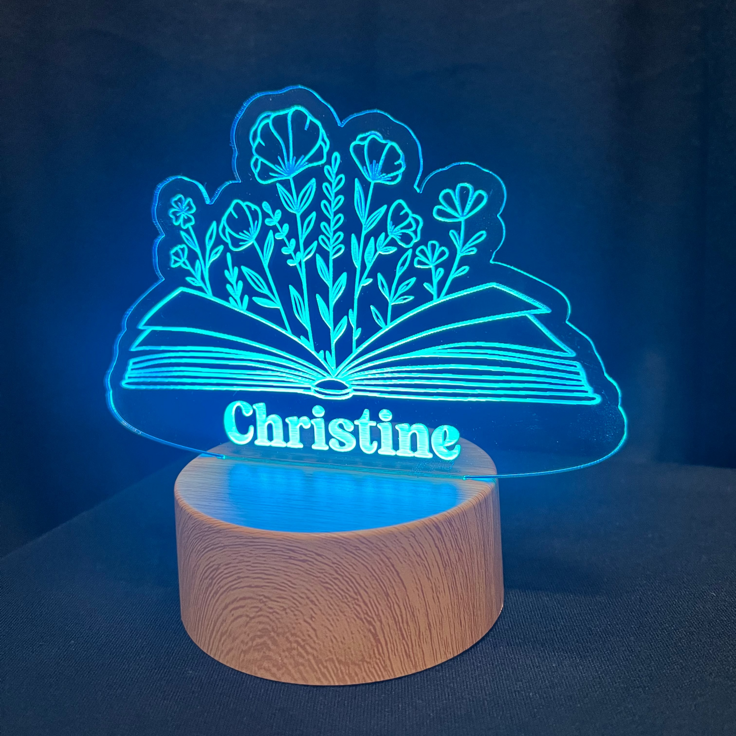 Decorative night light with a book and a floral design and 'Christine' text on a dark background