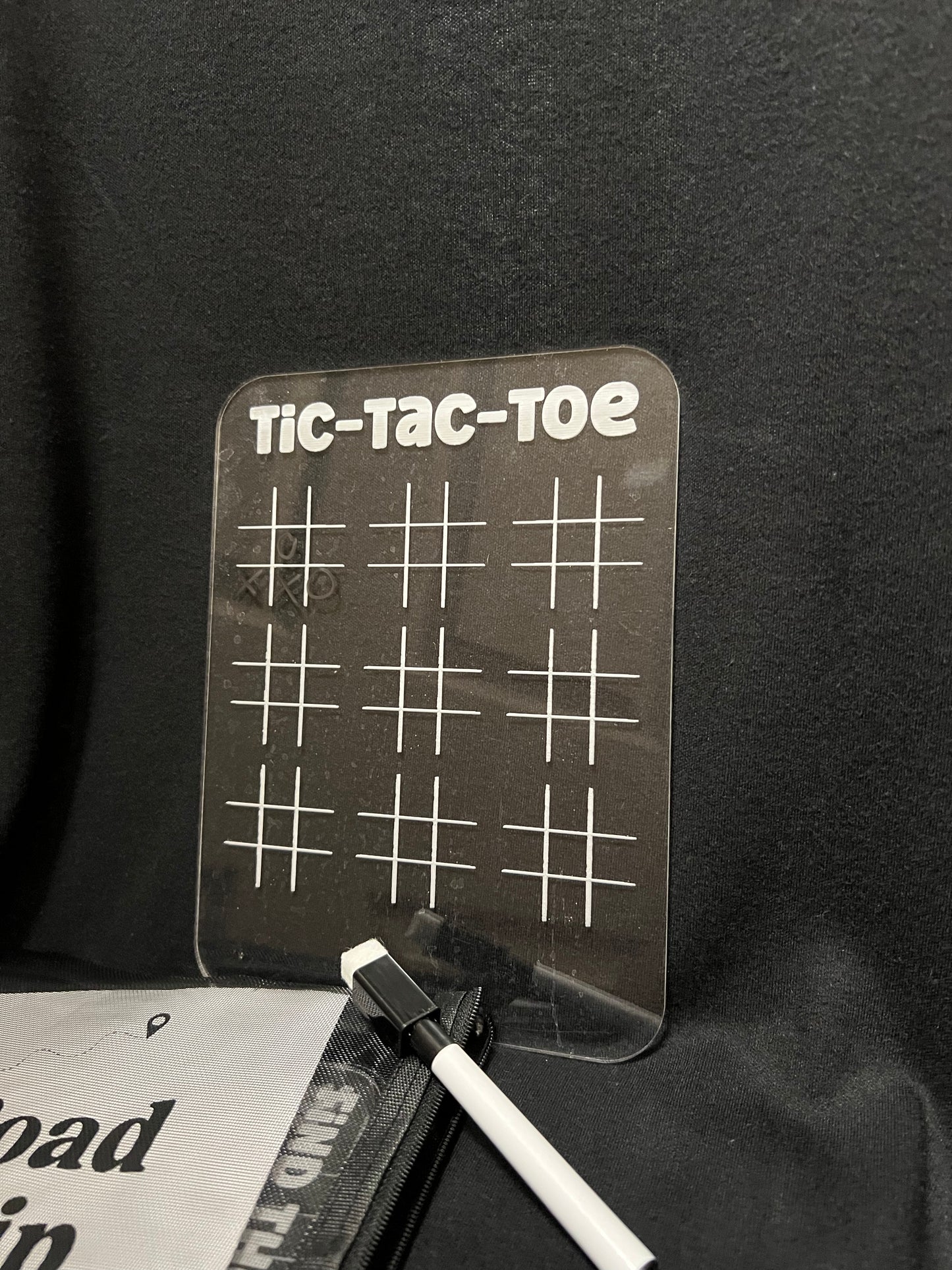 Clear tic-tac-toe board with a pen on a black background