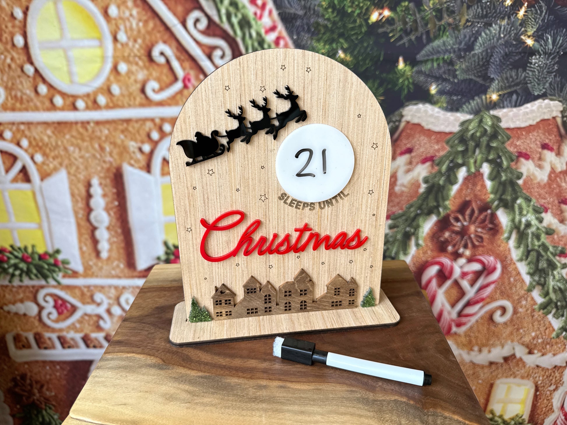 Small wooden sign with a dry erase moon that says (blank) sleeps until Christmas with Santa's sleigh and a holiday village 