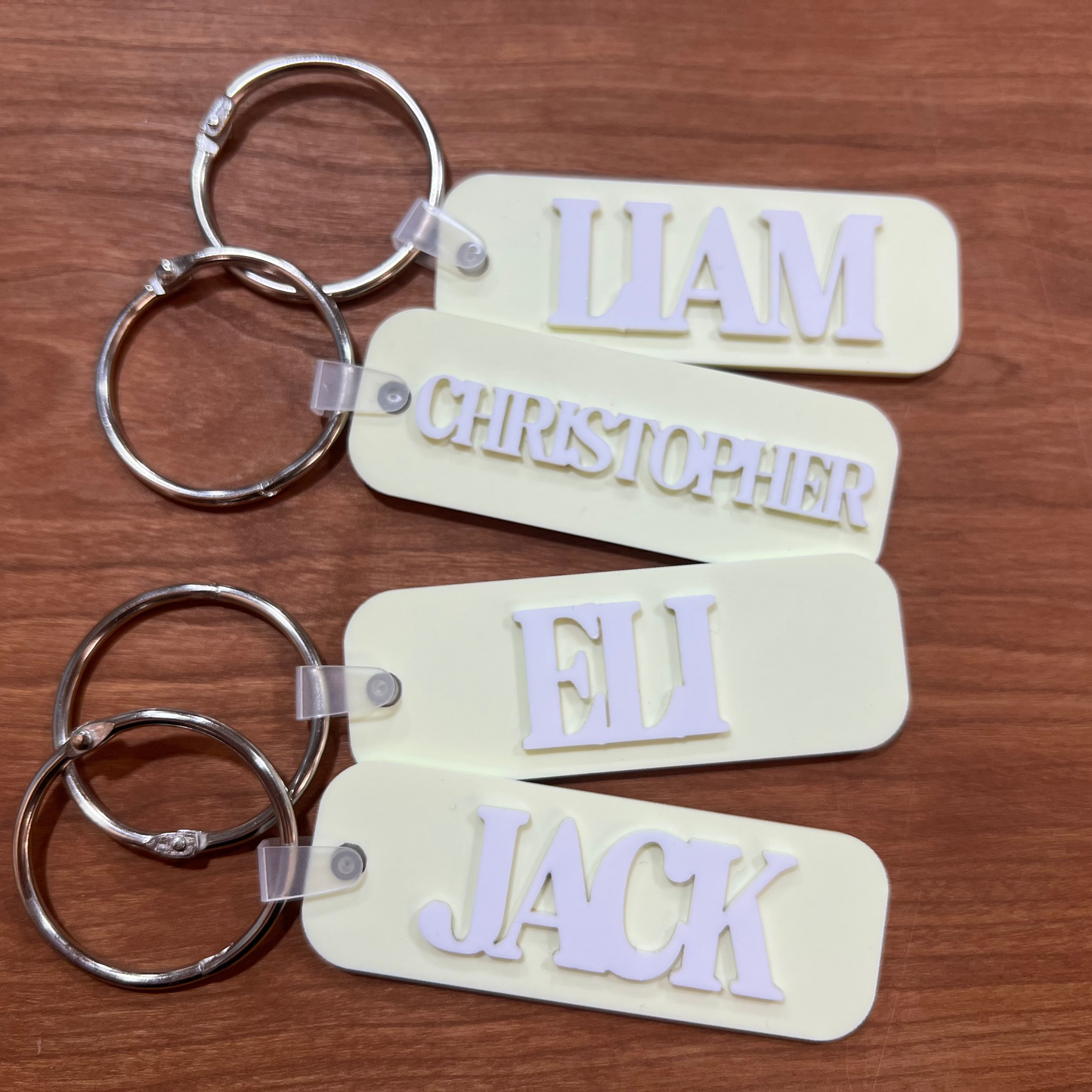 four yellow bag tags with names on them