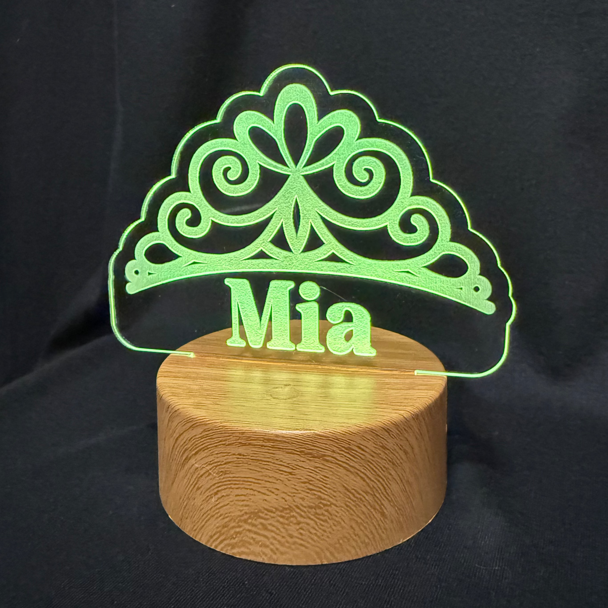 Decorative lamp with 'Mia' on a wooden base against a black background