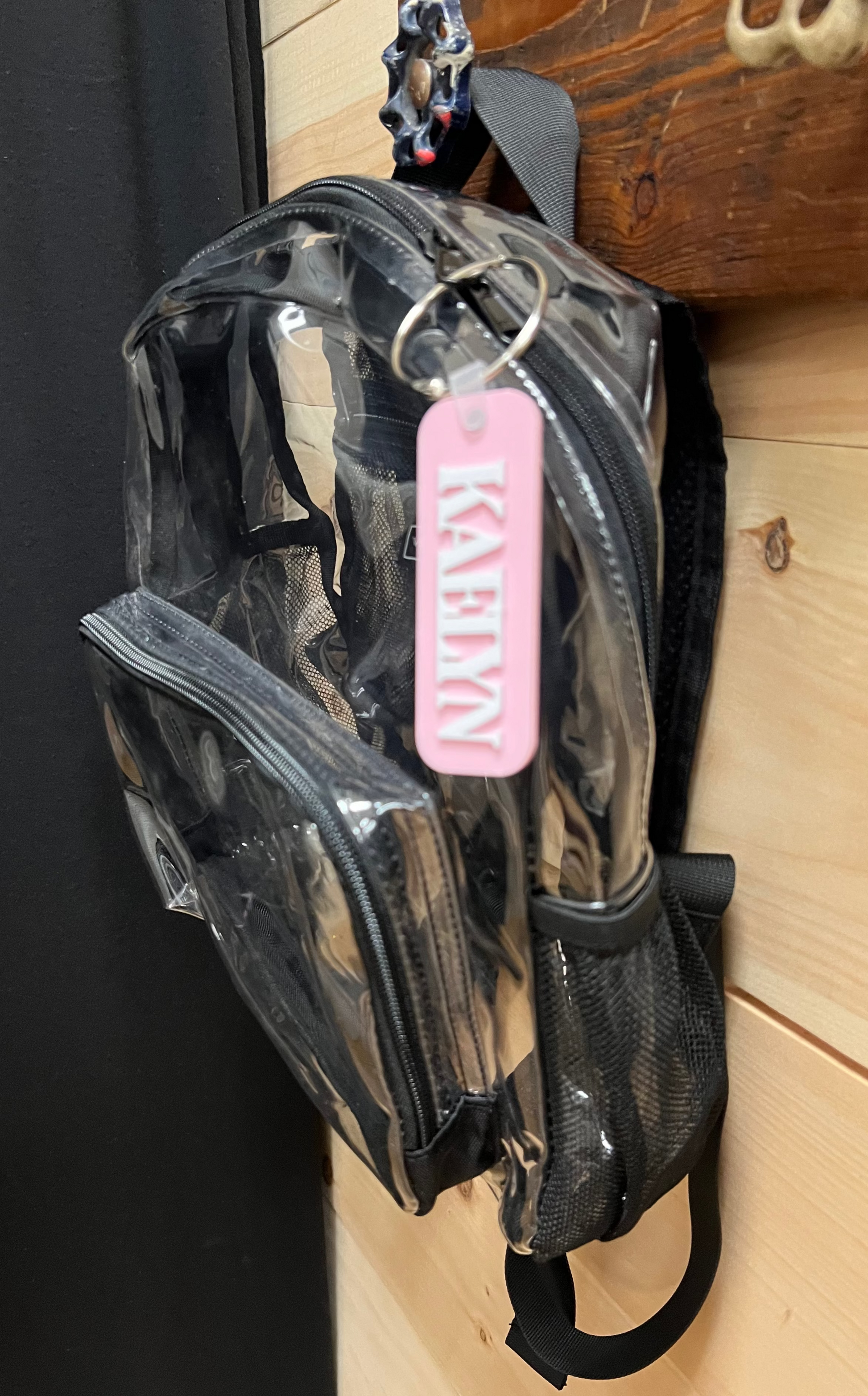 Clear plastic bag with a pink tag hanging on a wooden surface.