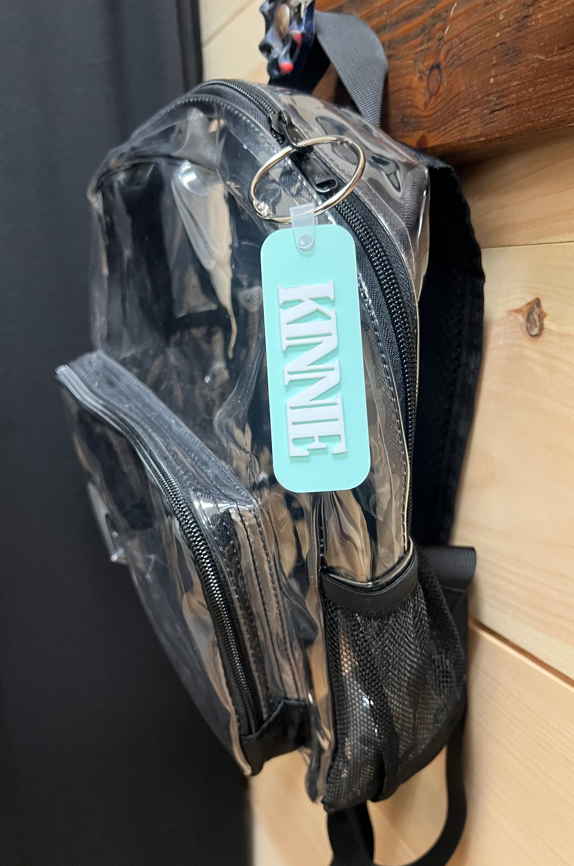 Clear backpack with a blue tag on a wooden surface