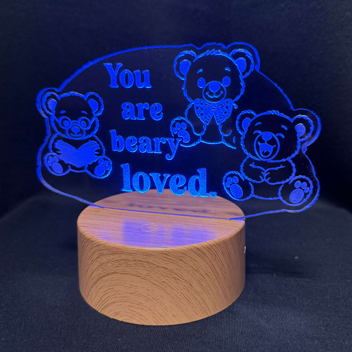 A wooden night light lamp with a glowing blue acrylic panel that reads 'You are beary loved.' and features three teddy bear illustrations, set against a dark background.