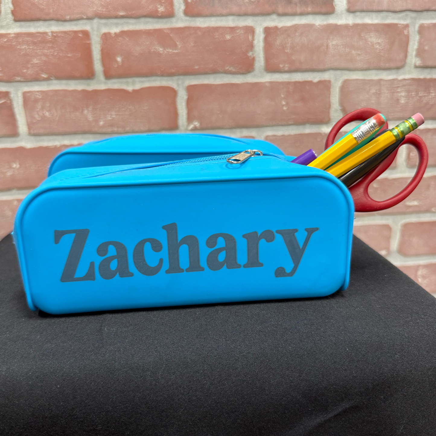 blue pencil pouch with the name Zachary engraved on it 