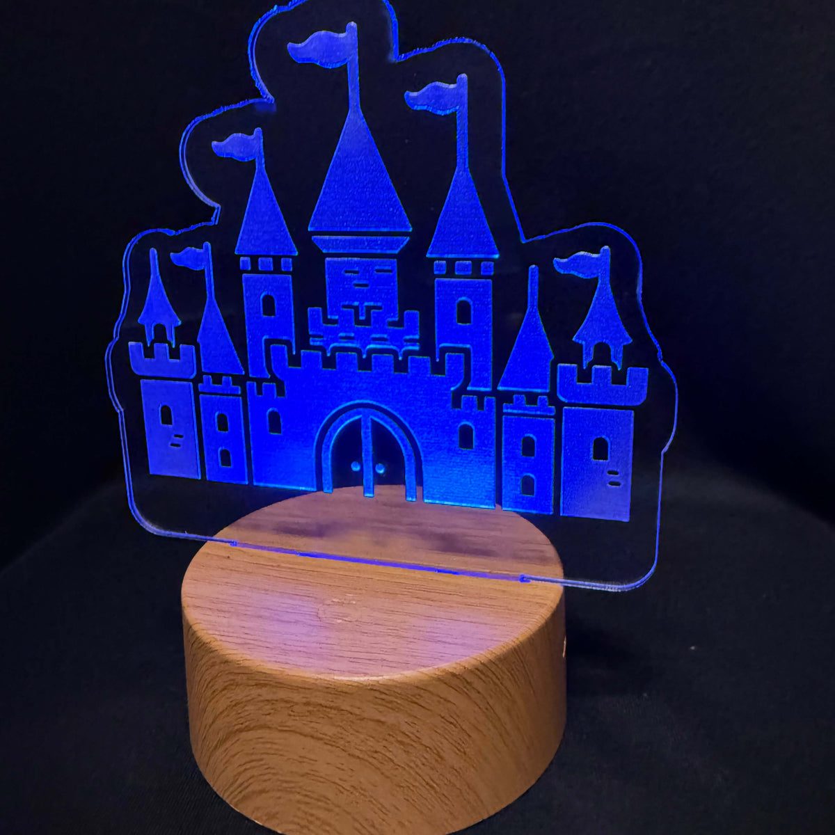Blue illuminated castle light on a round wood-style base. 
