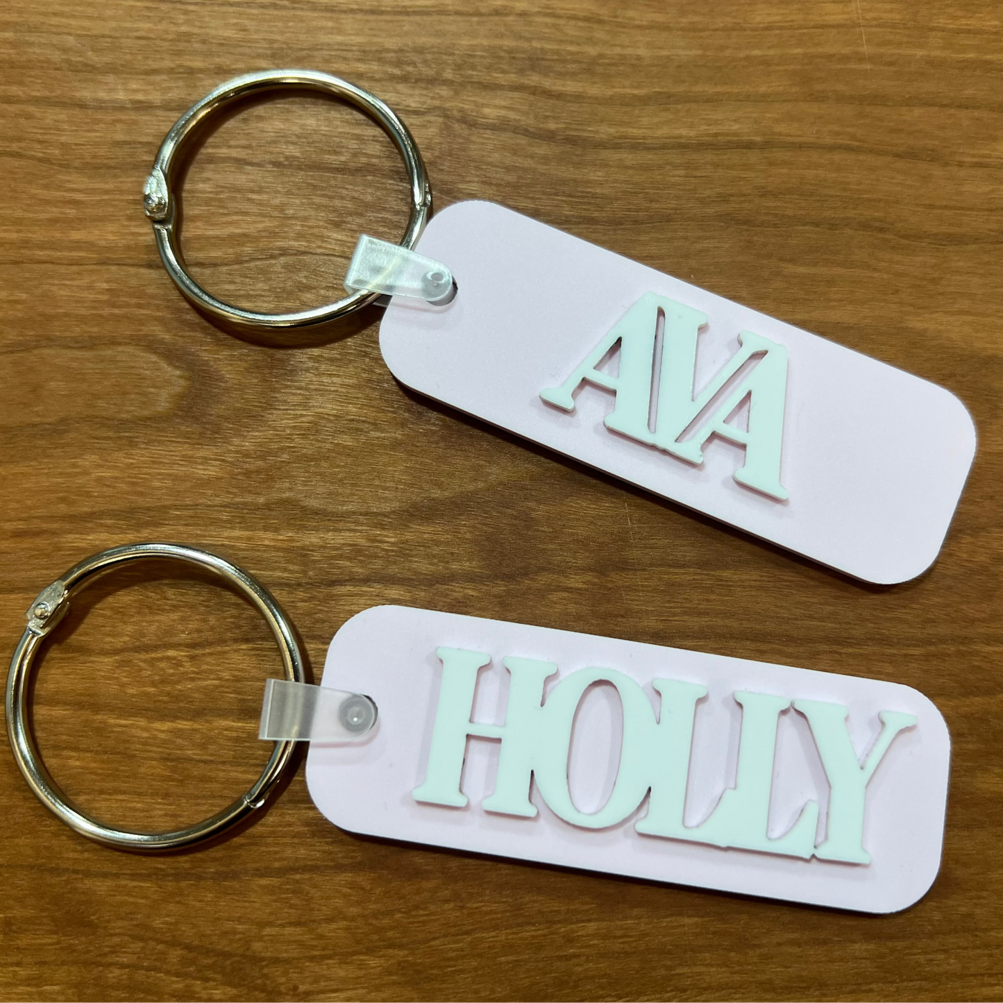 Two blush pink bag tags with the names Holly and Ava on them. 