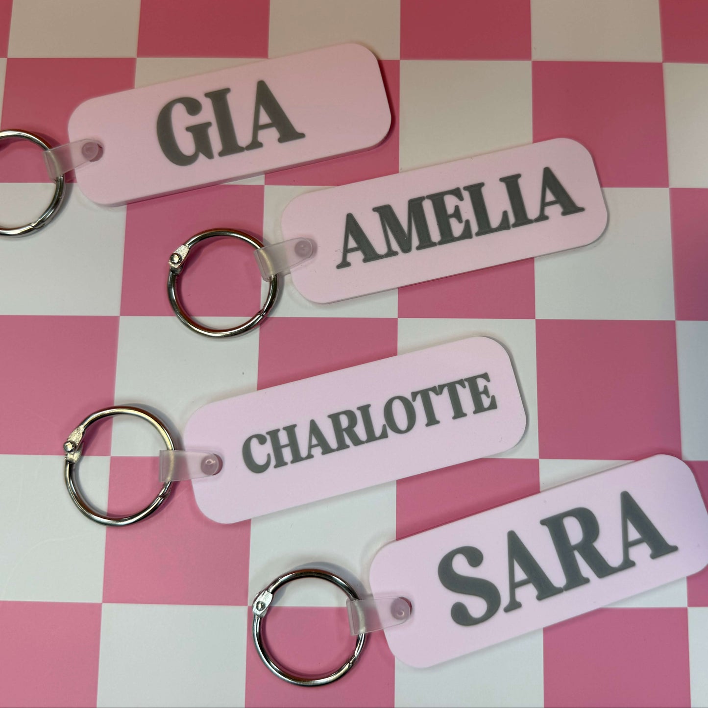 four light pink bag tags with names on them