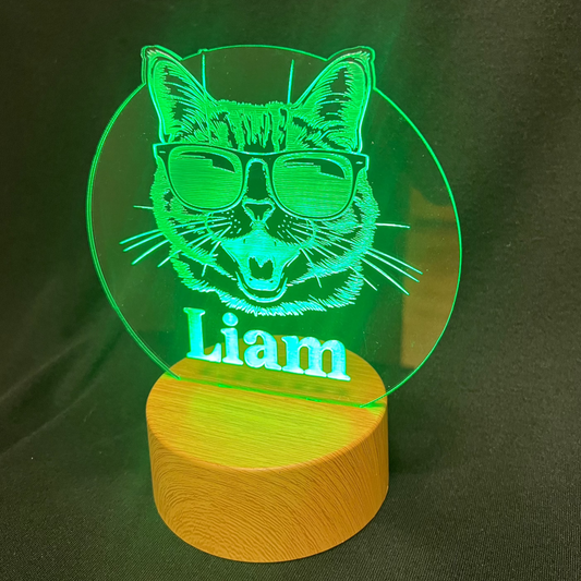 Cool Cat Night Light featuring a laser-engraved acrylic design of a cat wearing sunglasses, illuminated on a warm white LED base, with a personalized name beneath the cat