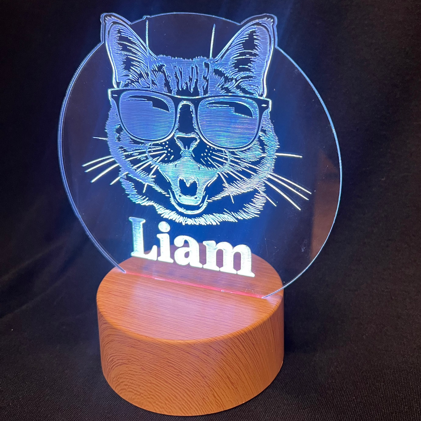 Cool Cat Night Light featuring a laser-engraved acrylic design of a cat wearing sunglasses, illuminated on a warm white LED base, with a personalized name beneath the cat