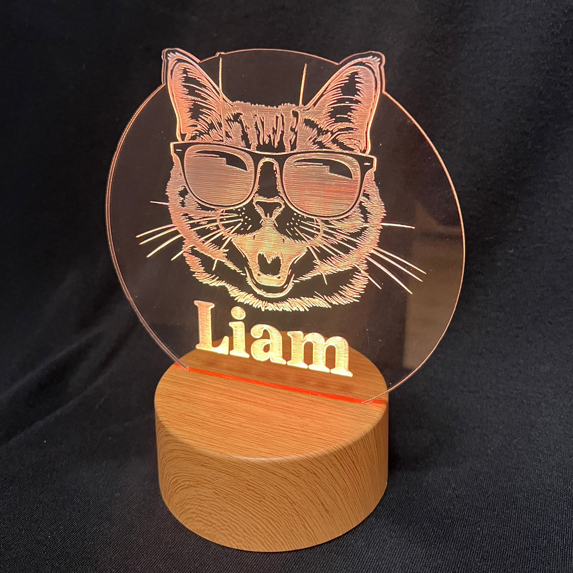 Cool Cat Night Light featuring a laser-engraved acrylic design of a cat wearing sunglasses, illuminated on a warm white LED base, with a personalized name beneath the cat