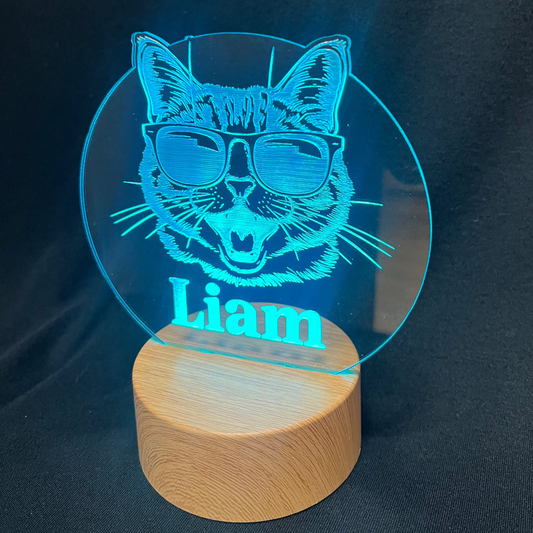 Cool Cat Night Light featuring a laser-engraved acrylic design of a cat wearing sunglasses, illuminated on a warm white LED base, with a personalized name beneath the cat
