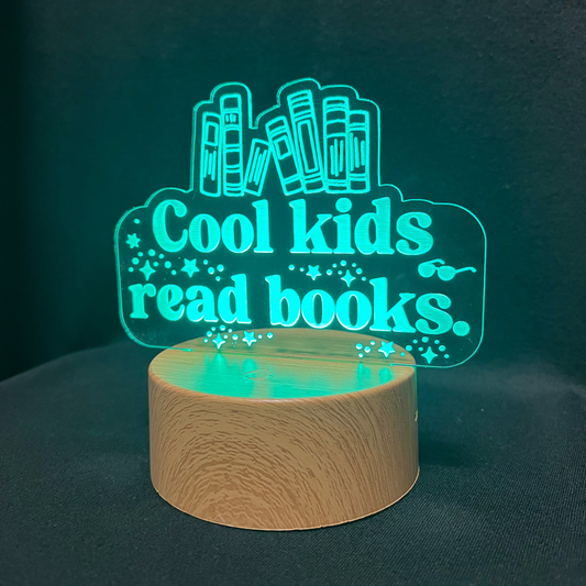 Decorative night light with 'Cool kids read books' text and book illustrations on a black background.