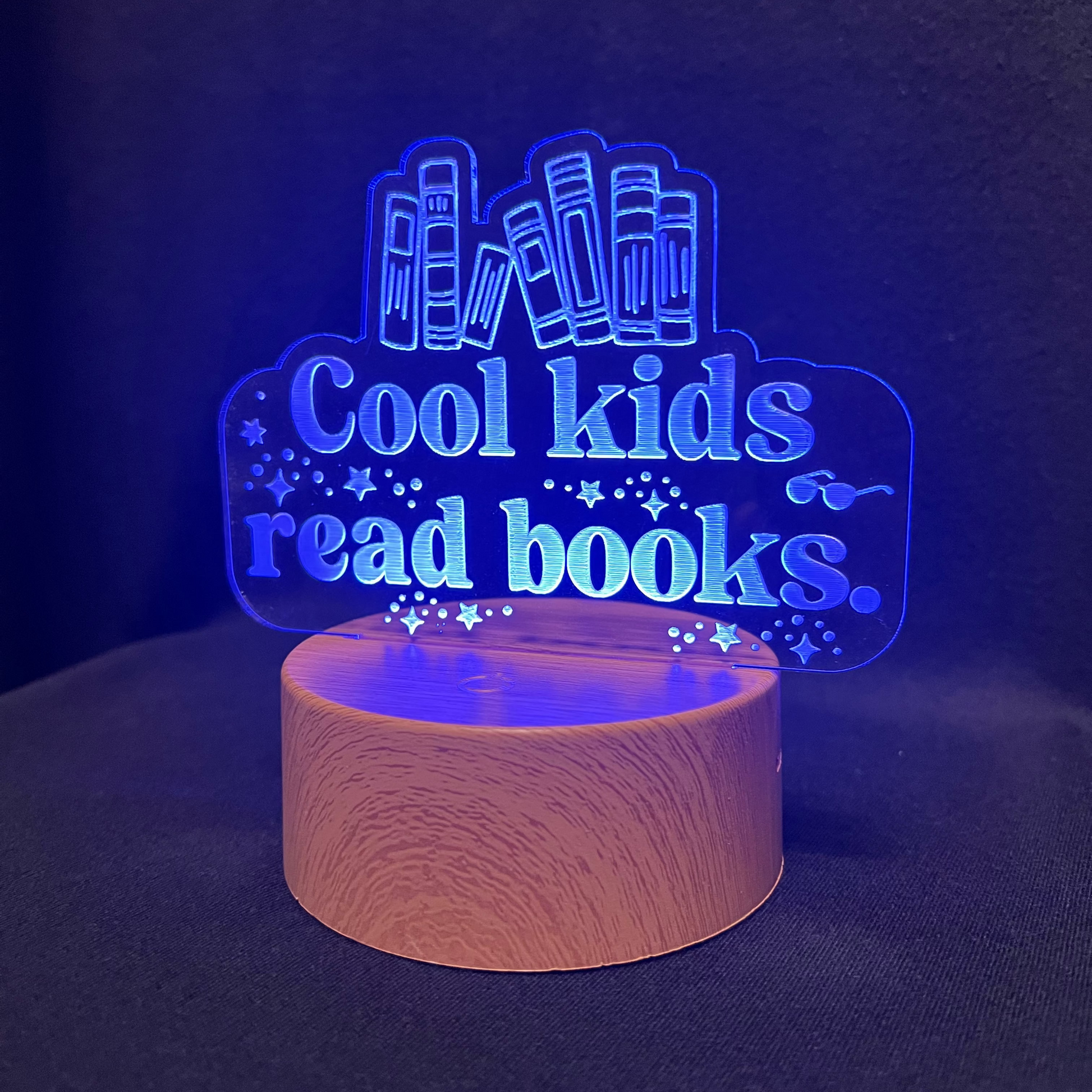 Decorative night light with 'Cool kids read books' text and book illustrations on a black background.