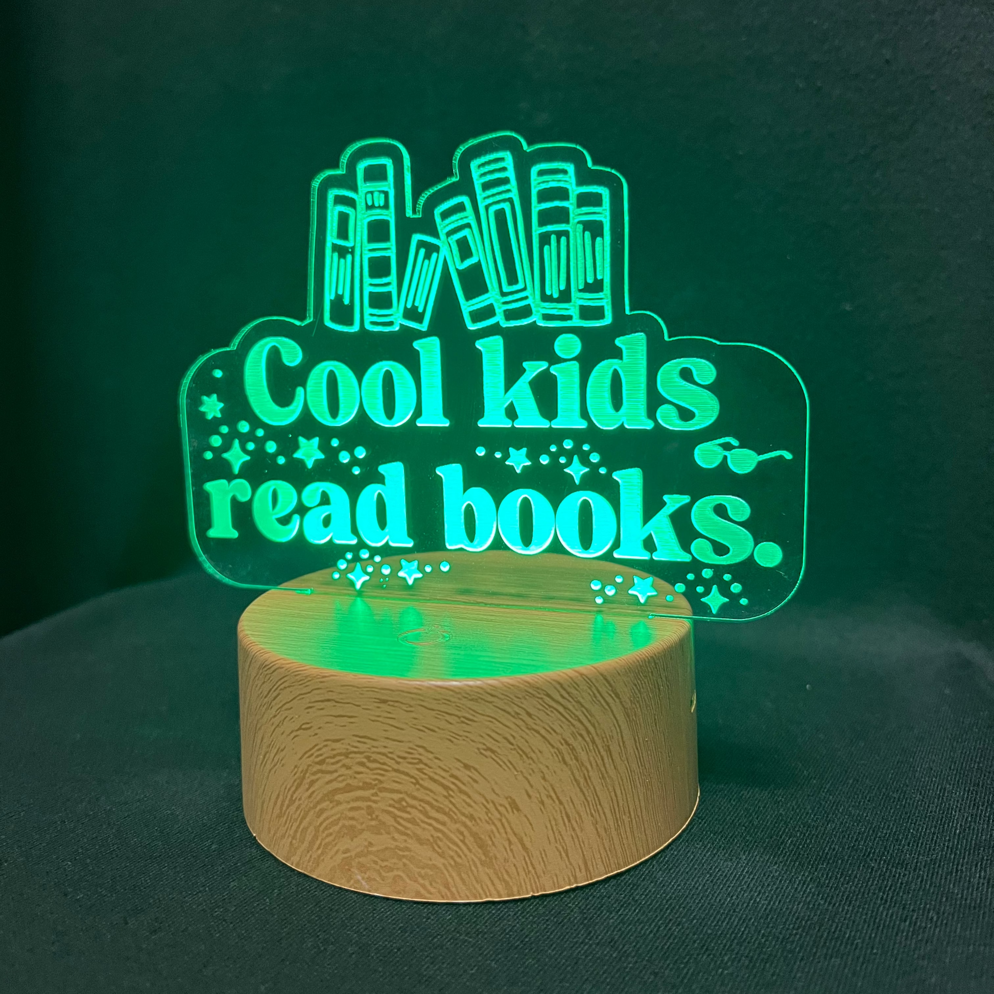 Decorative night light with 'Cool kids read books' text and book illustrations on a black background.