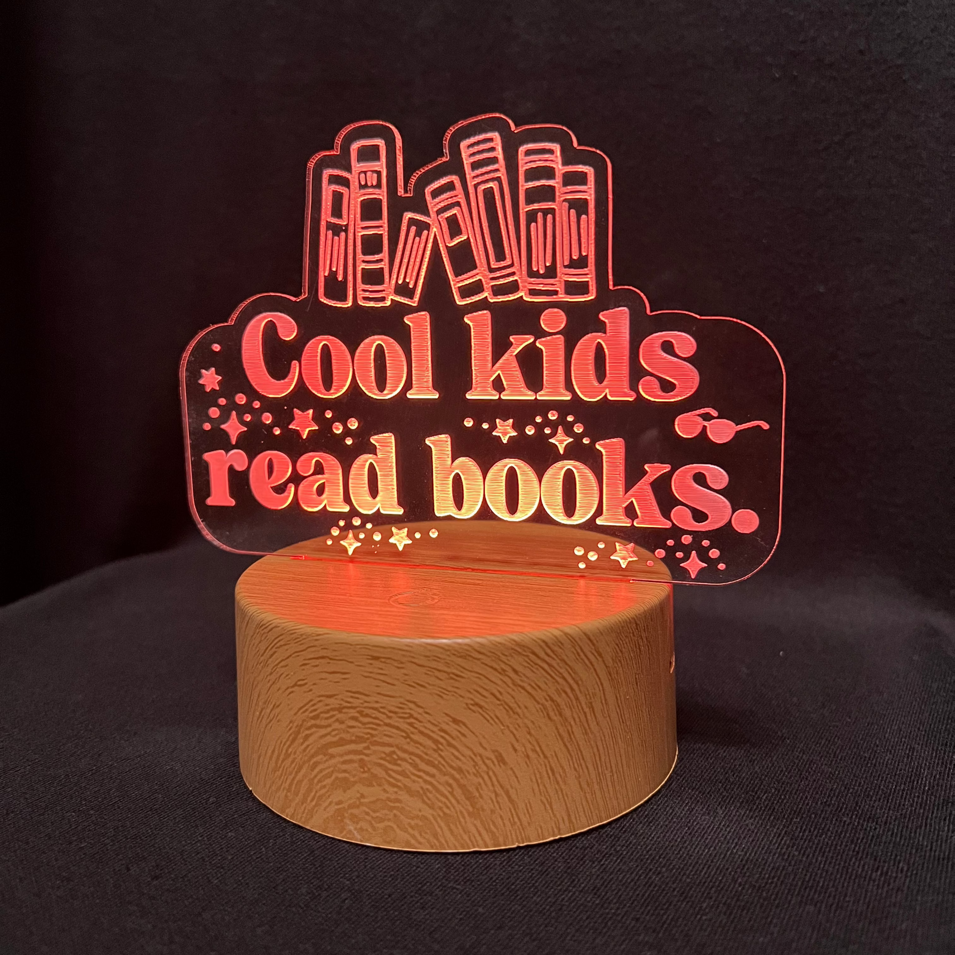 Decorative night light with 'Cool kids read books' text and book illustrations on a black background.
