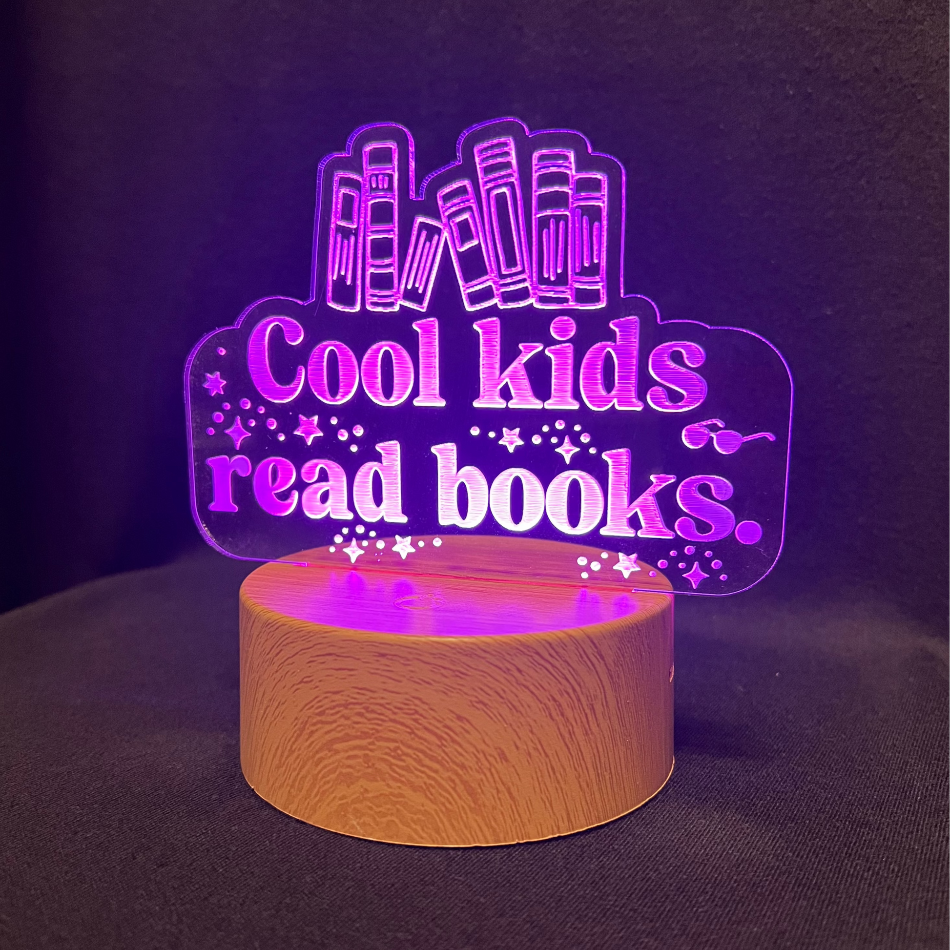 Decorative night light with 'Cool kids read books' text and book illustrations on a black background.