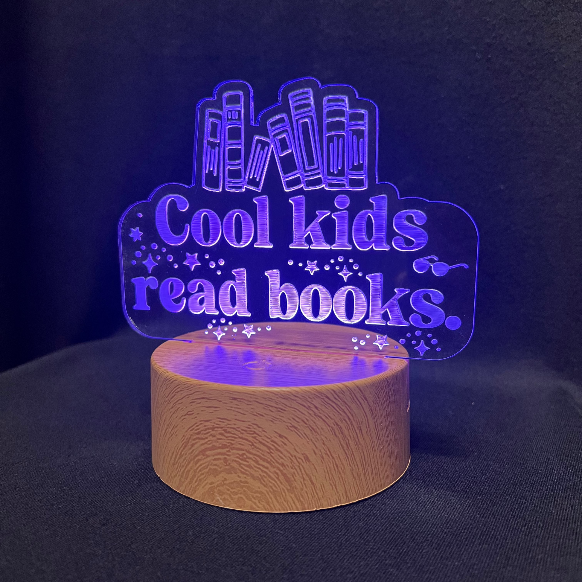 Decorative night light with 'Cool kids read books' text and book illustrations on a black background.