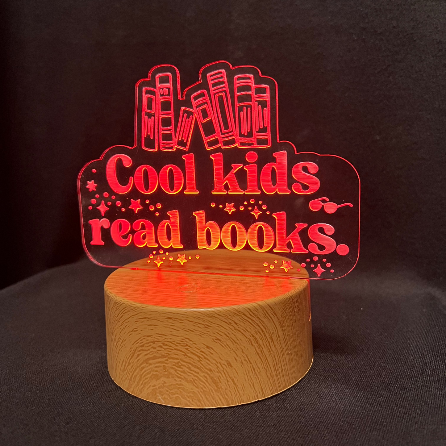 Decorative night light with 'Cool kids read books' text and book illustrations on a black background.