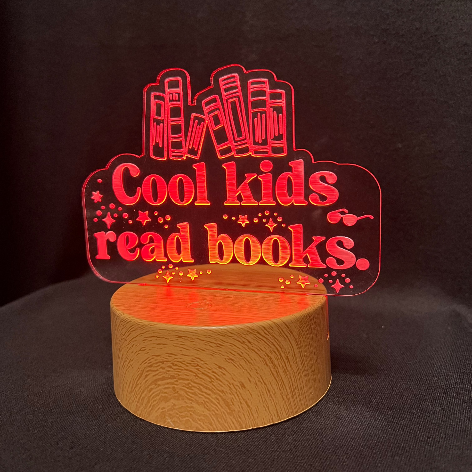 Decorative night light with 'Cool kids read books' text and book illustrations on a black background.