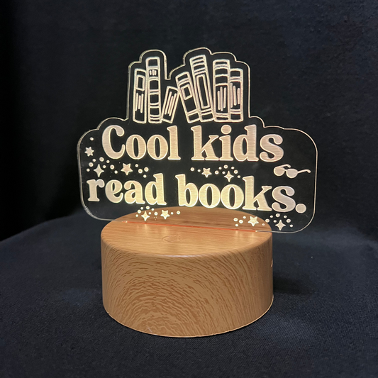 Decorative night light with 'Cool kids read books' text and book illustrations on a black background.