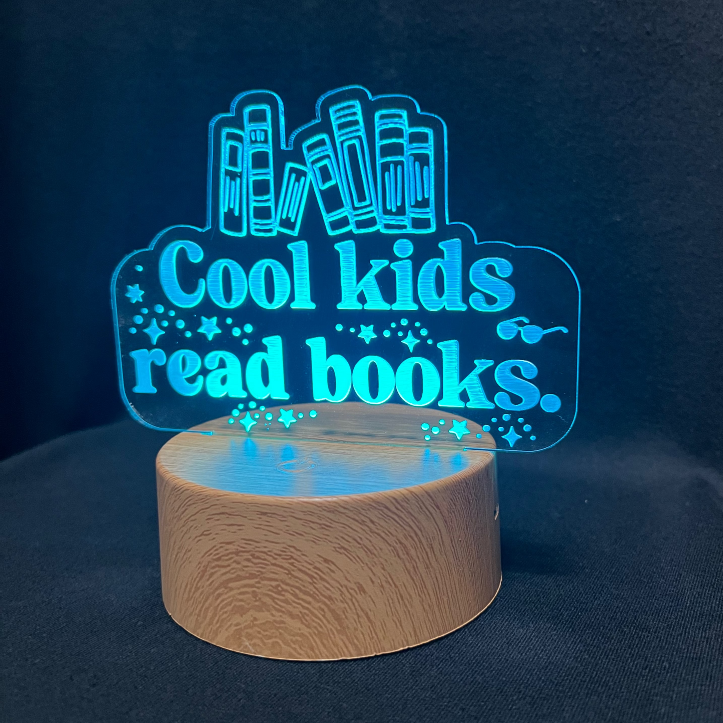Decorative night light with 'Cool kids read books' text and book illustrations on a black background.