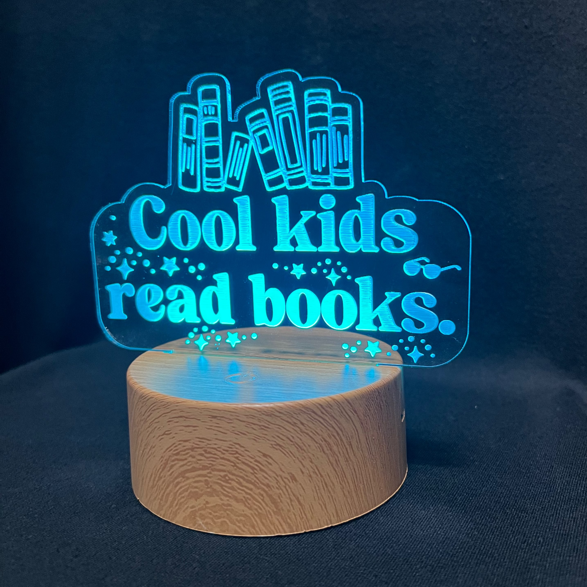 Decorative night light with 'Cool kids read books' text and book illustrations on a black background.