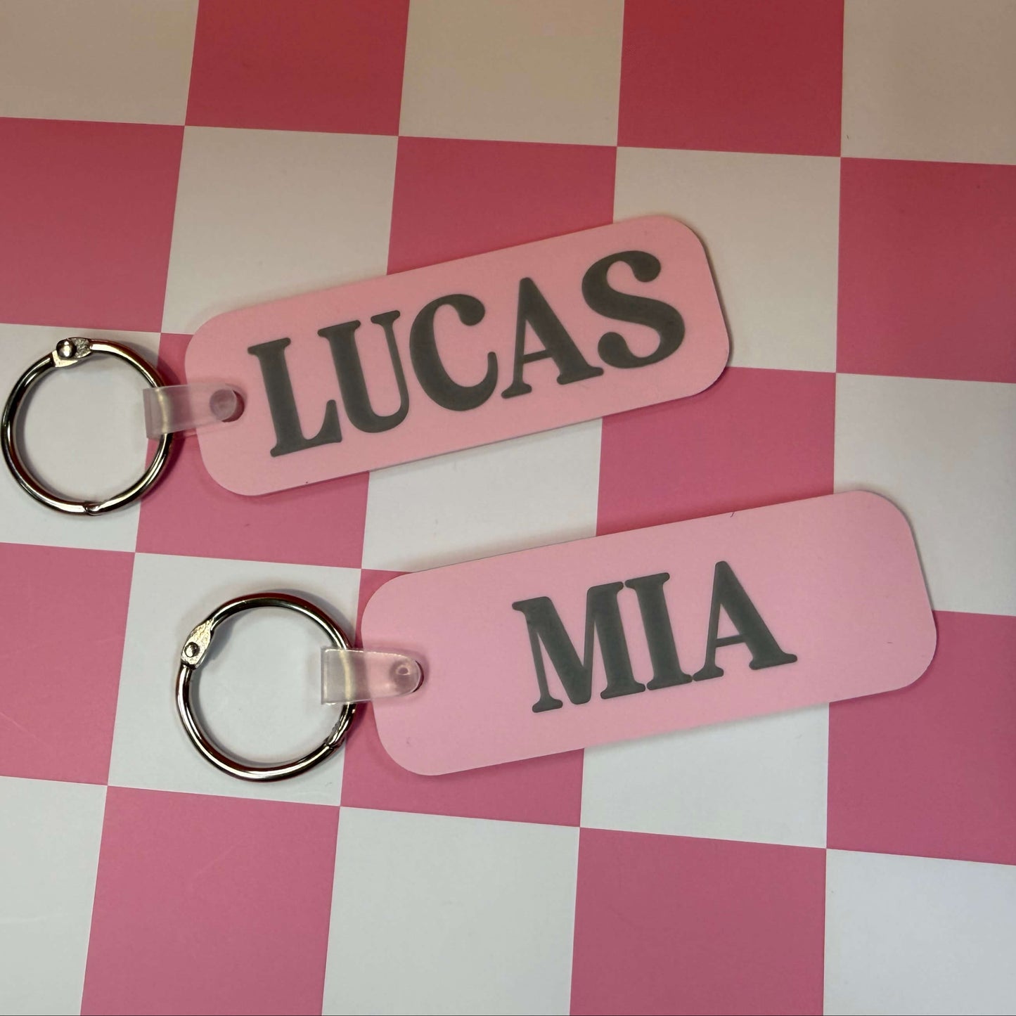 two pink bag tags with names on them