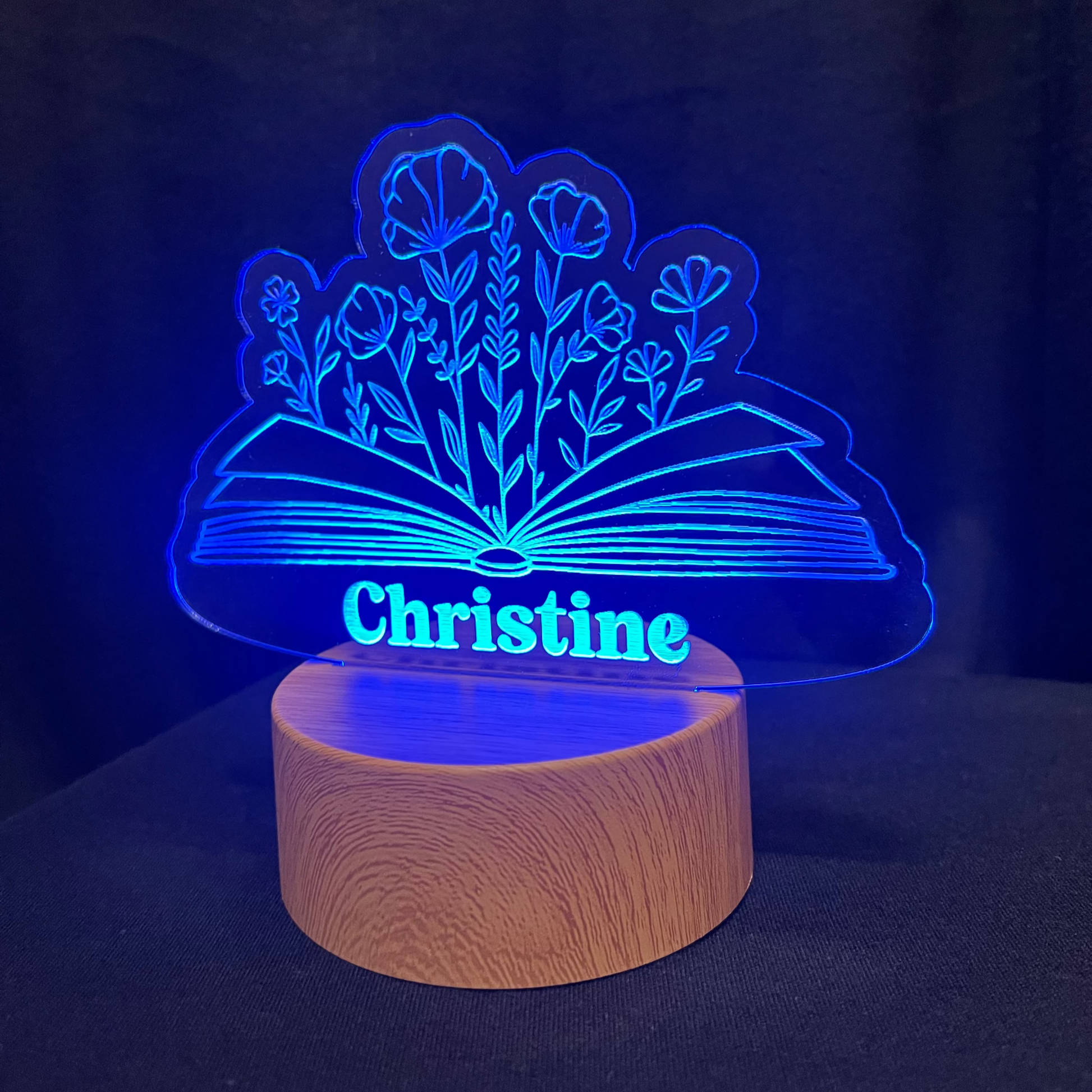 LED lamp with floral design and book and wooden base on a dark background