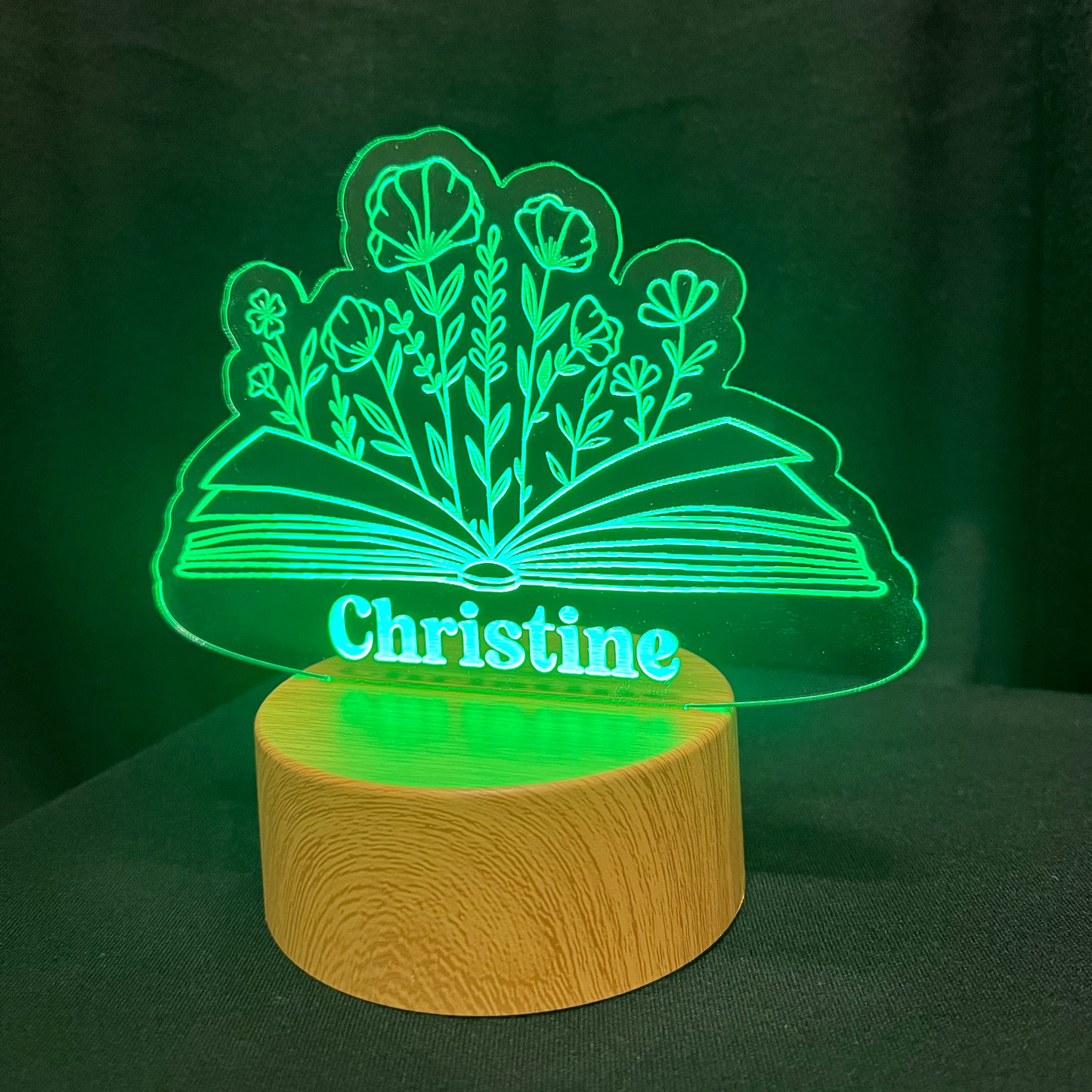 LED lamp with 'Christine' and a floral book design on a wooden base against a dark background