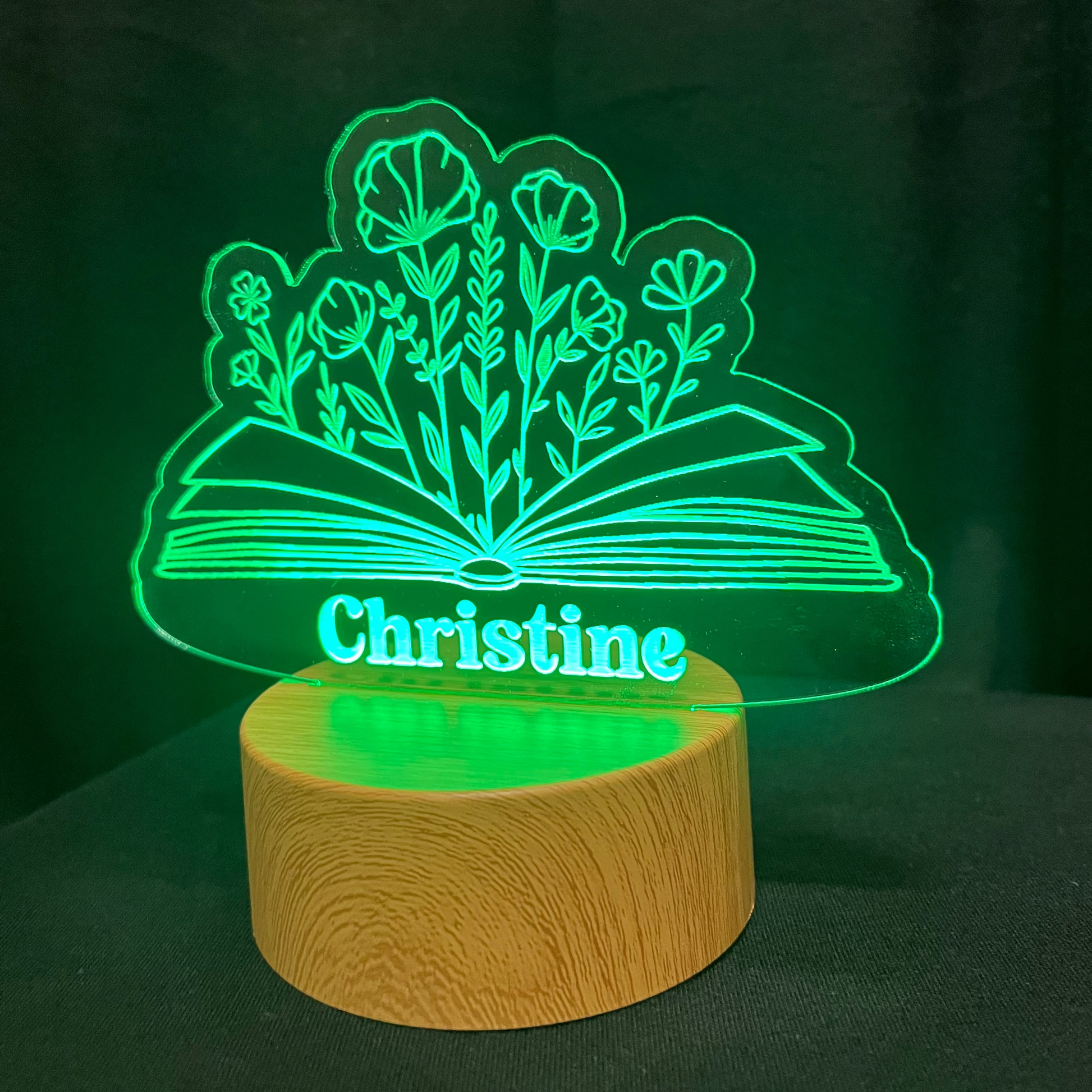 Decorative lamp with 'Christine' and a floral book design on a dark background