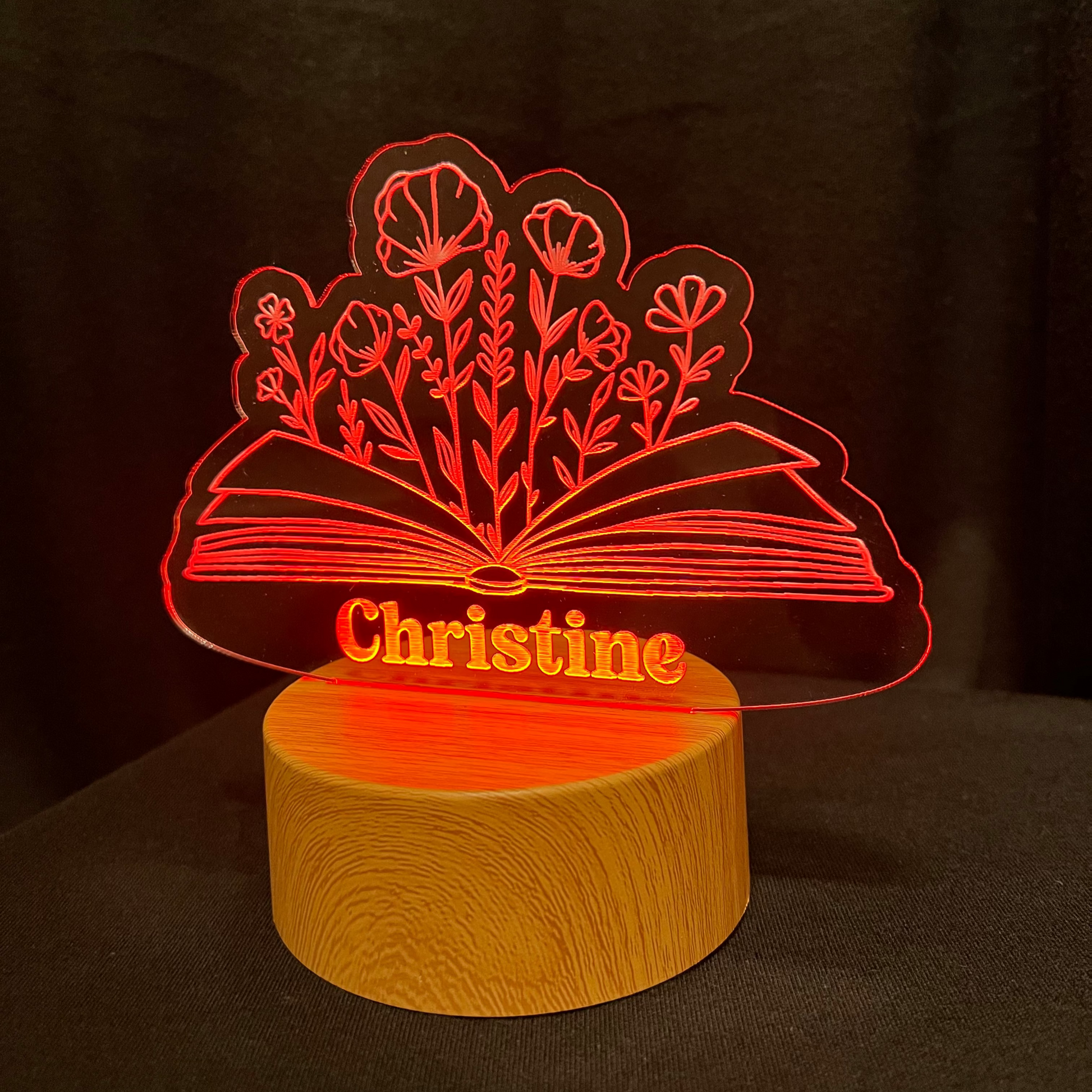 LED lamp with floral design and book and 'Christine' text on a dark background