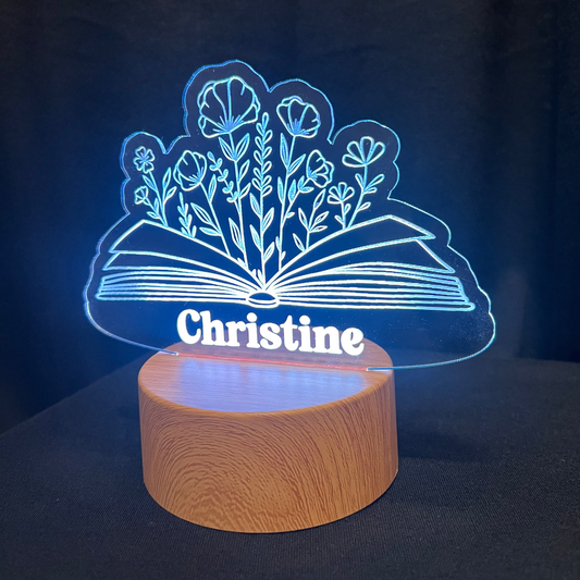 Decorative lamp with 'Christine' and book with floral design on a dark background