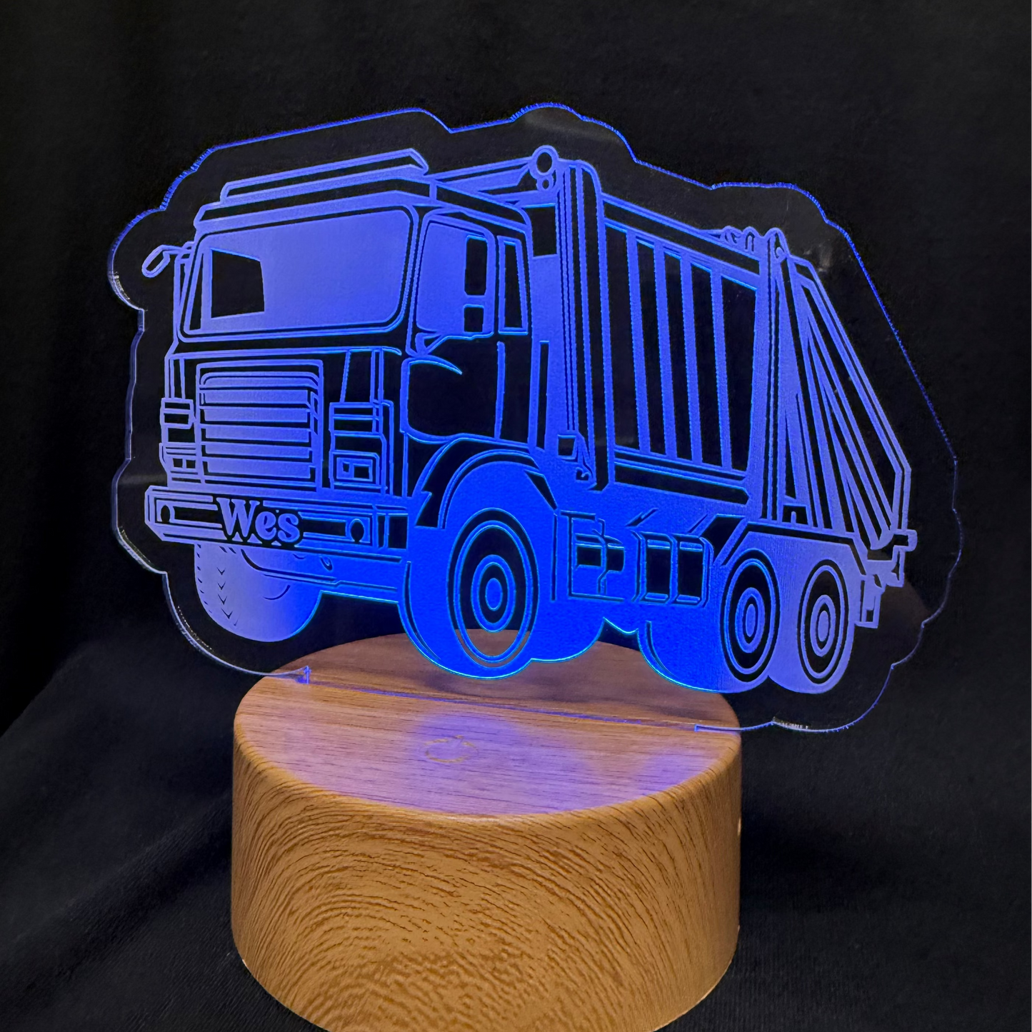 LED lamp shaped like a dump truck on a wooden base with a black background