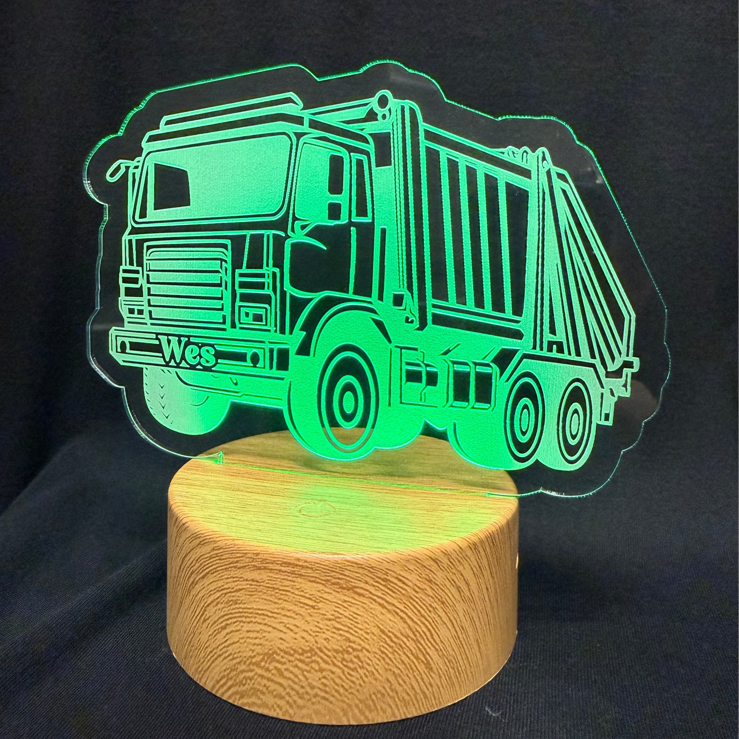 Garbage truck-shaped night light on a wooden base with a black background