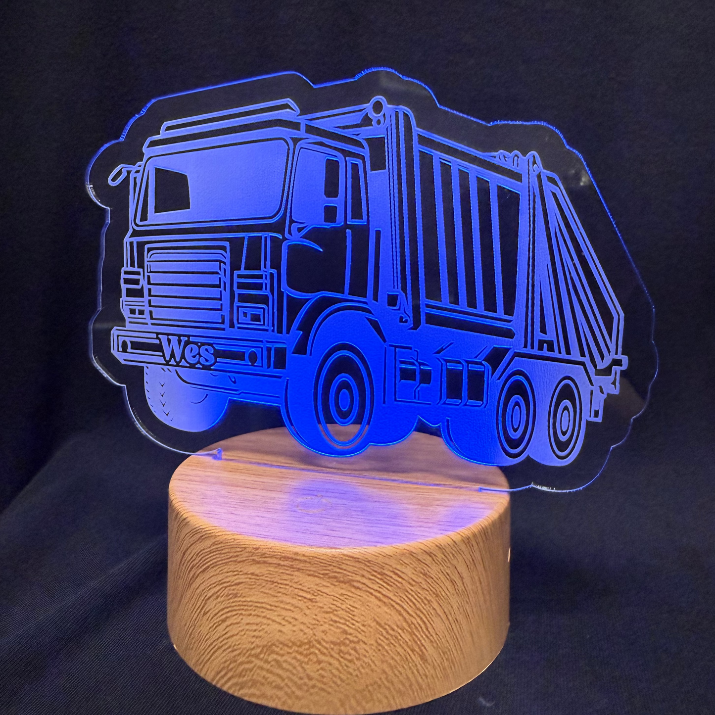 Garbage truck-shaped night light with wooden base on a dark background