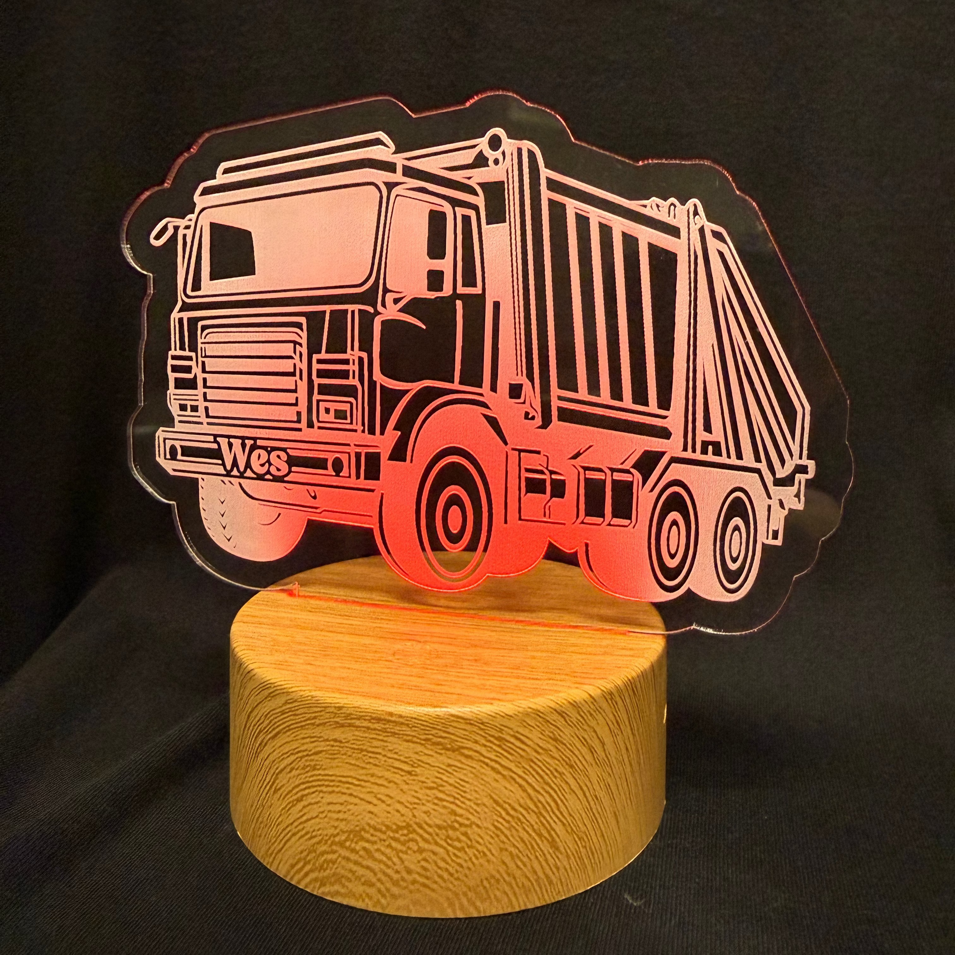 Night light shaped like a dump truck with a wooden base on a black background