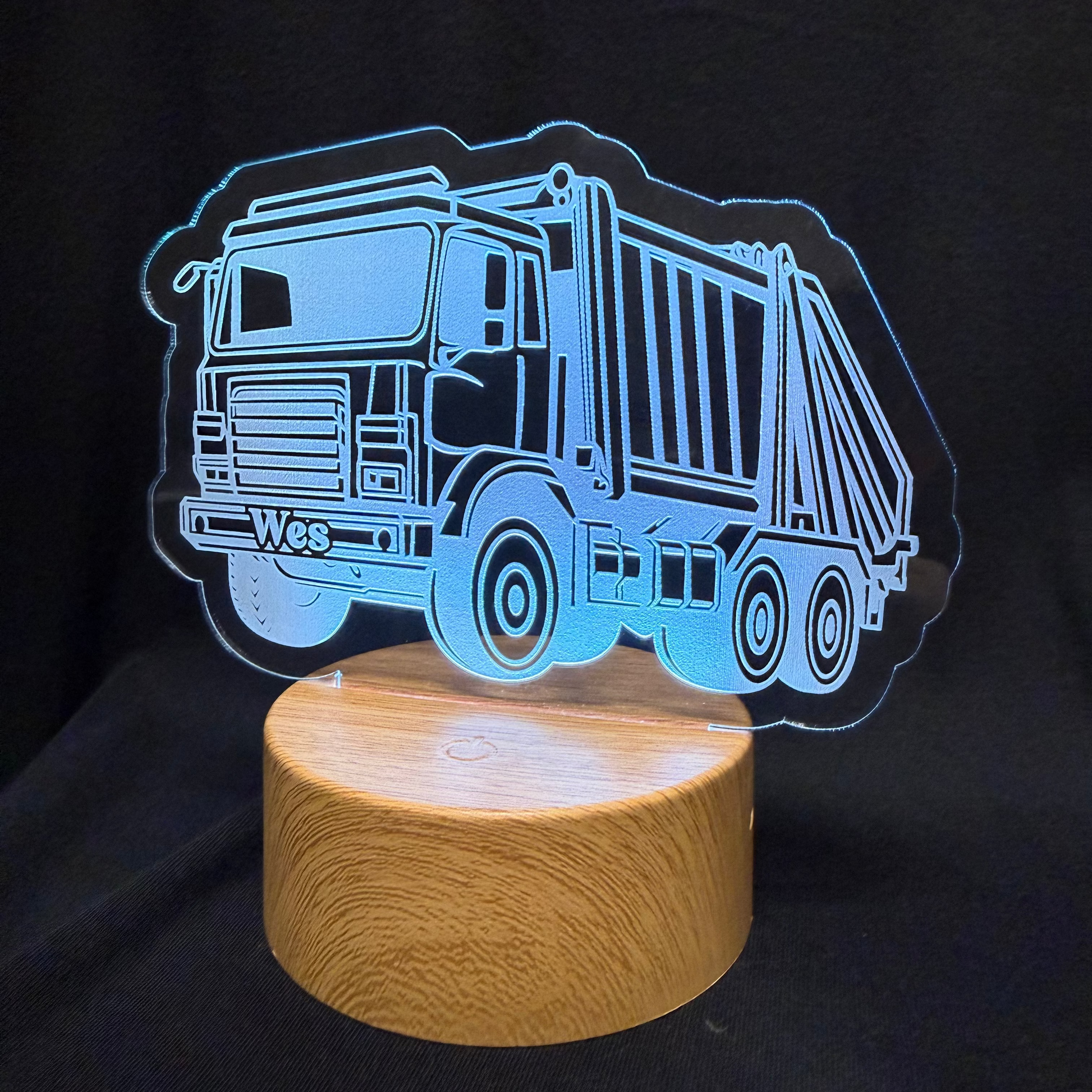 Garbage truck-shaped night light on a wooden base with a black background