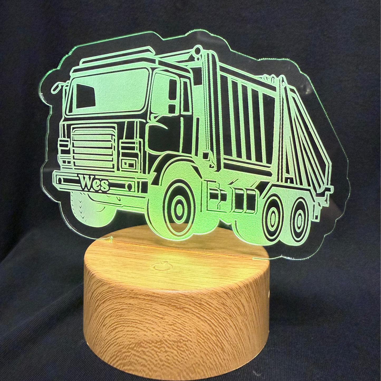 Garbage truck-shaped night light on a wooden base against a dark background