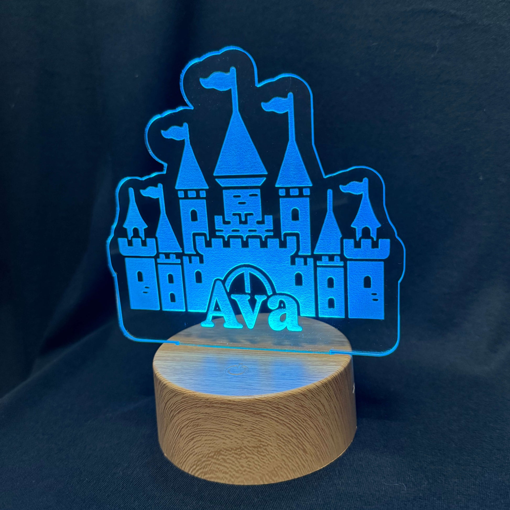 Castle-shaped night light with 'Ava' on a wooden base against a dark background