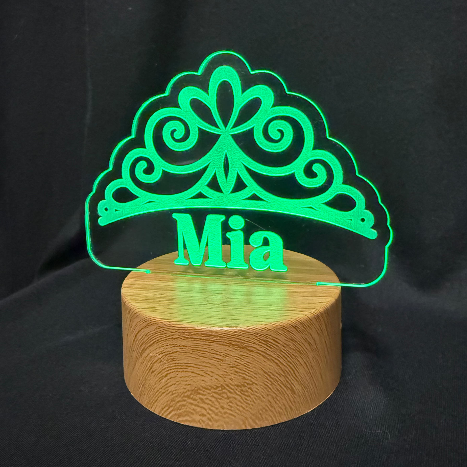 Decorative lamp with green clover design and 'Mia' text on a black background