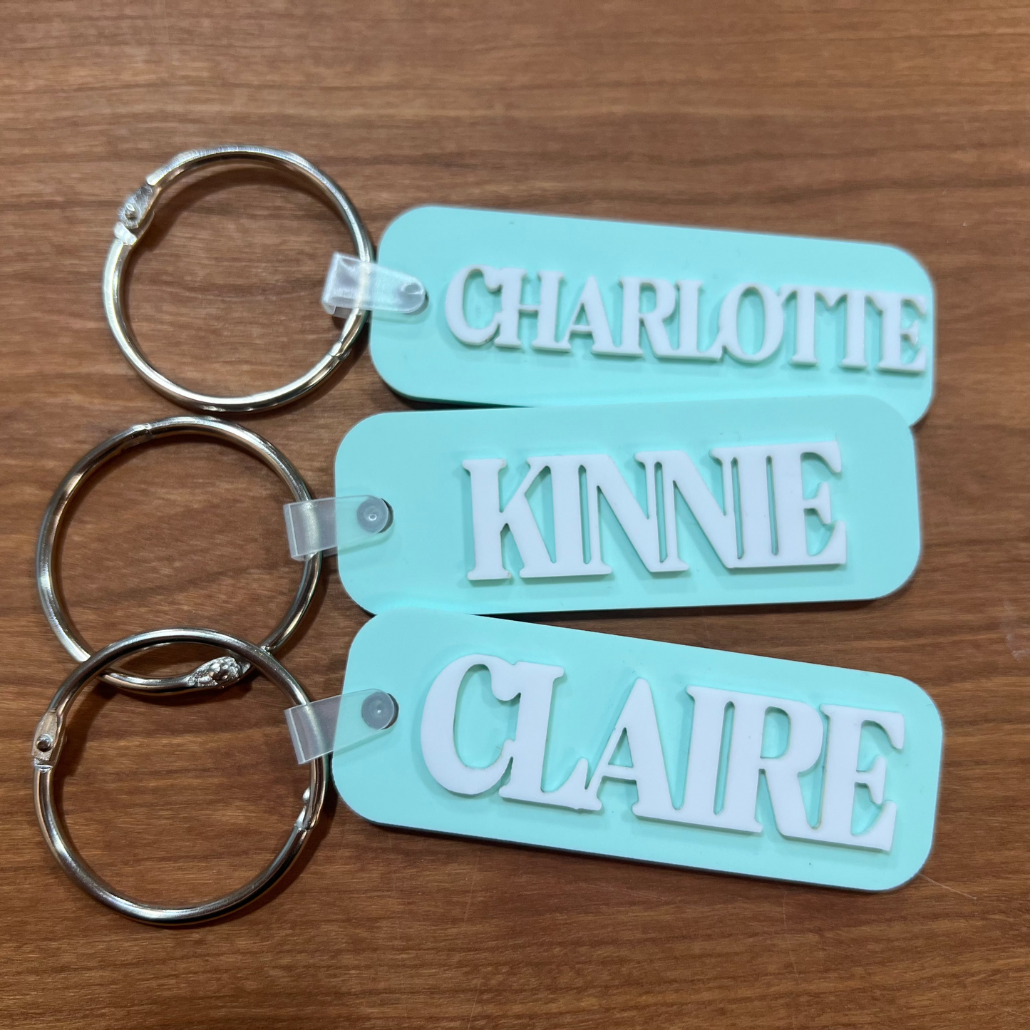 Three mint green colored bag tags with names on them