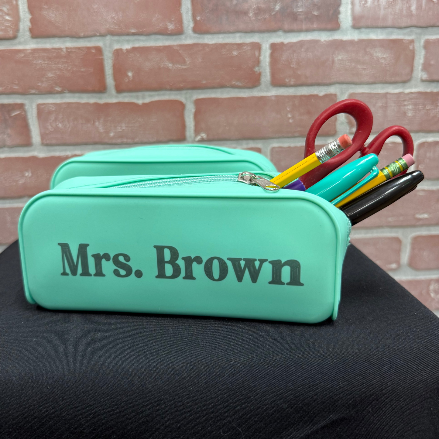 mint colored pencil pouch with pencils and markers in it with the name Mrs. Brown engraved on the front