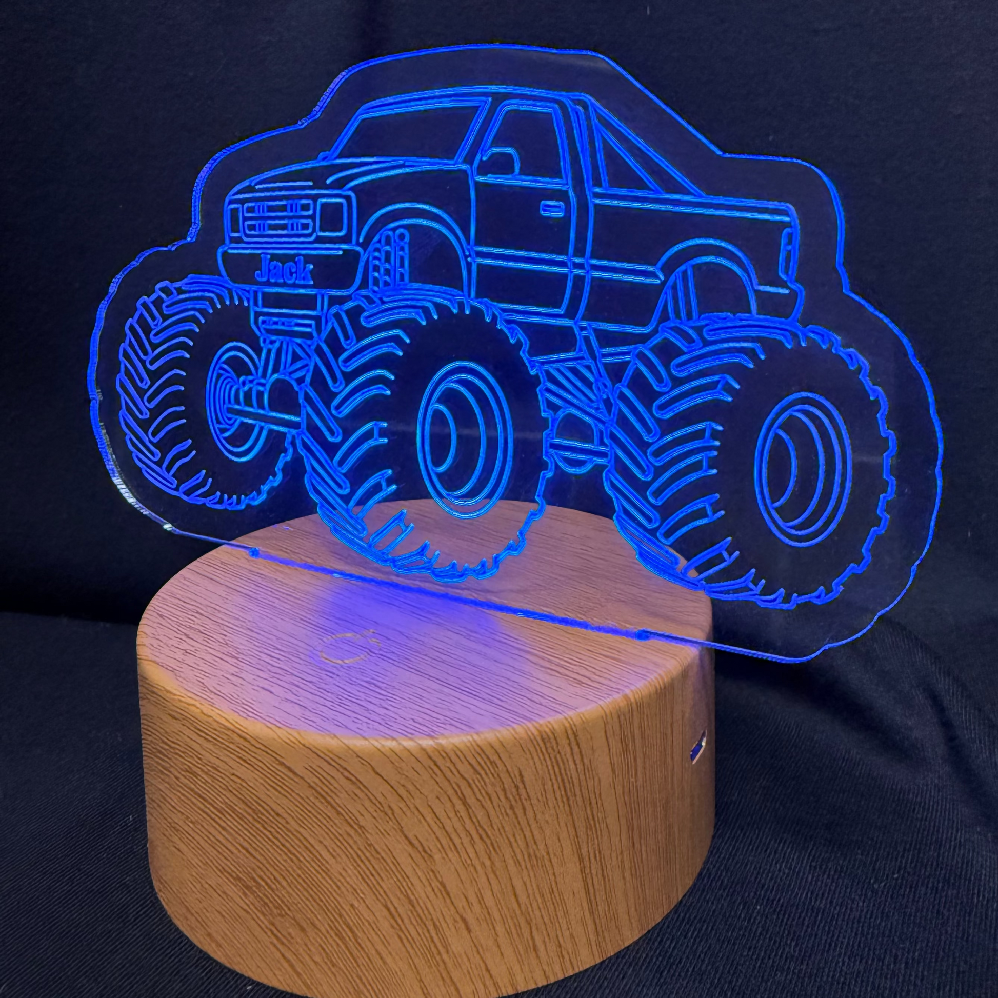 Monster truck-shaped night light on a wooden base with a dark background