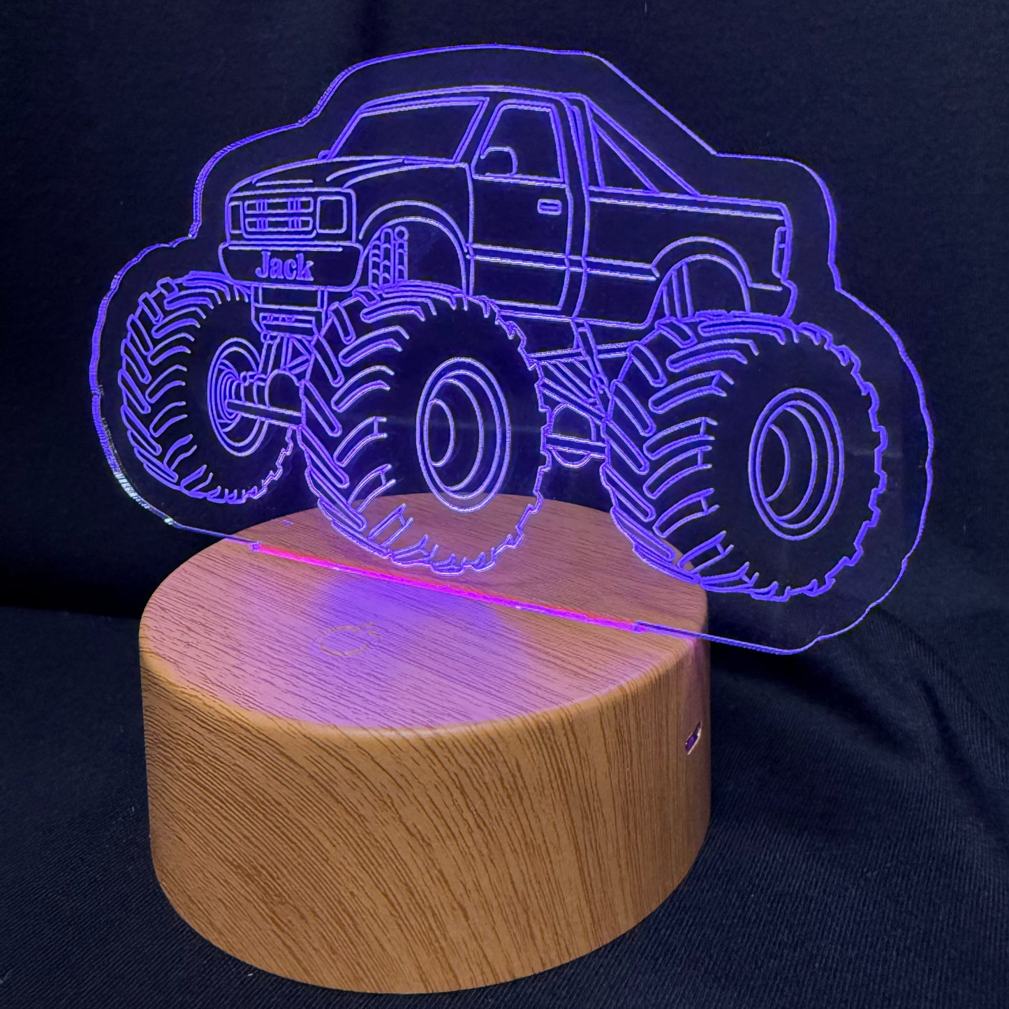 Monster truck design night light on a wooden base against a dark background