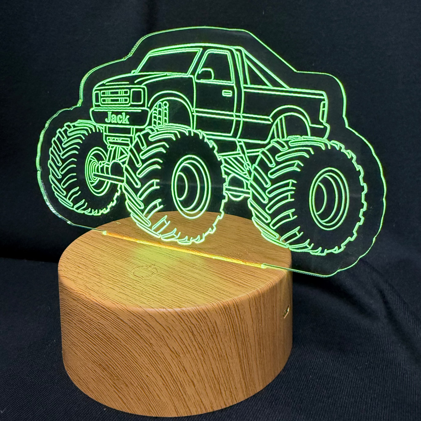 Monster truck design on a wooden base with green outline against a black background
