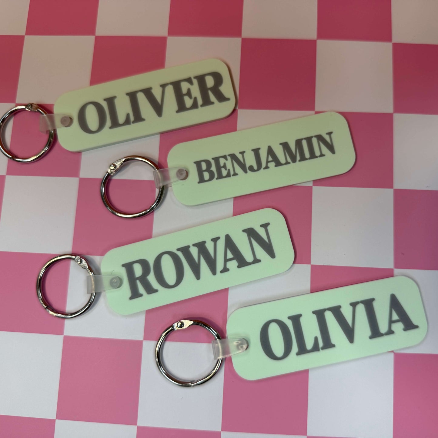 four green bag tags with names on a checkered background