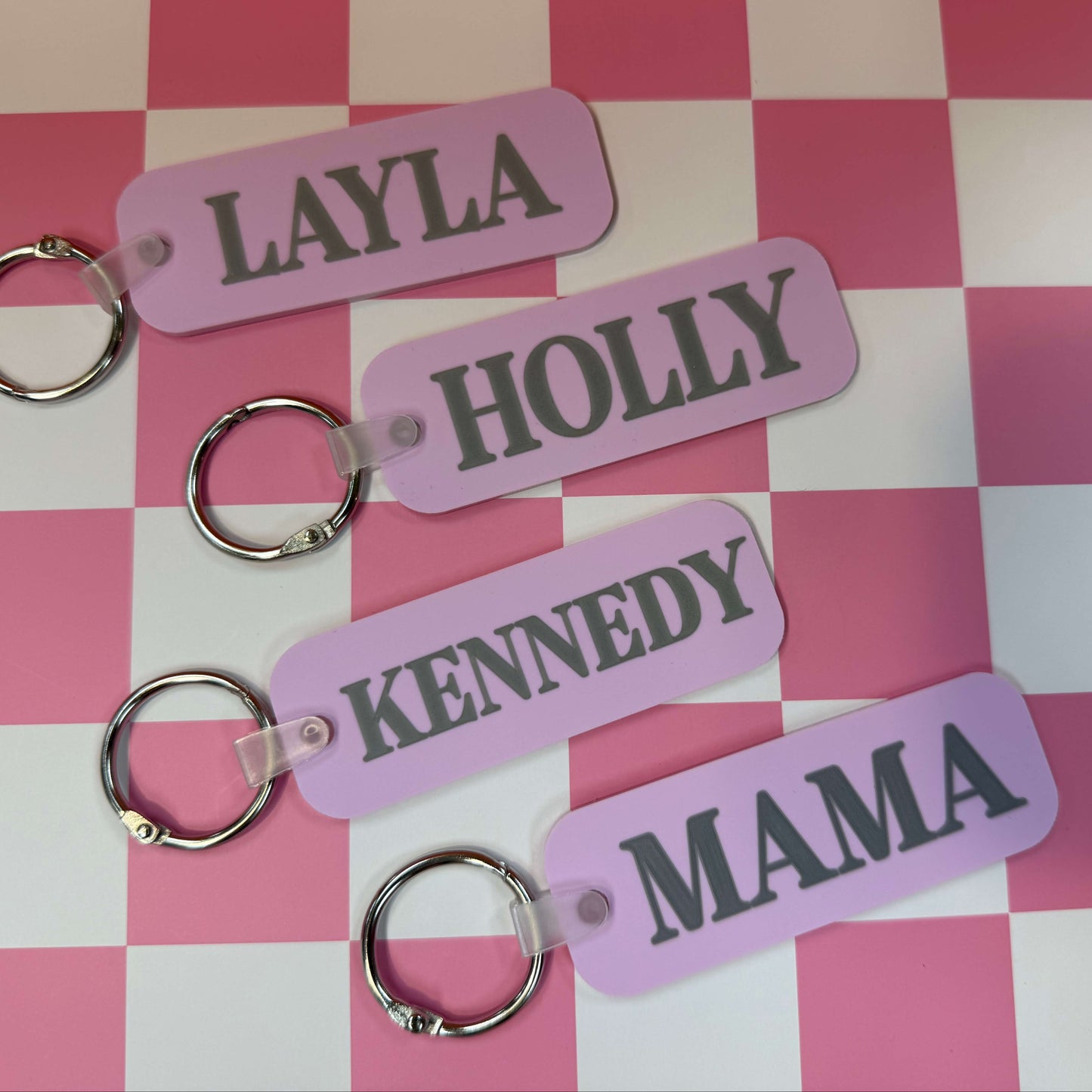 four purple bag tags with names on them 