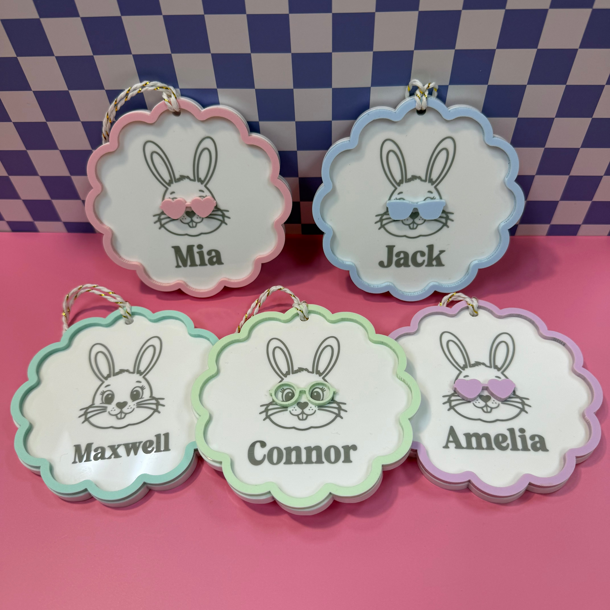 Five decorative name tags with cartoon rabbit faces and names against a checkered background