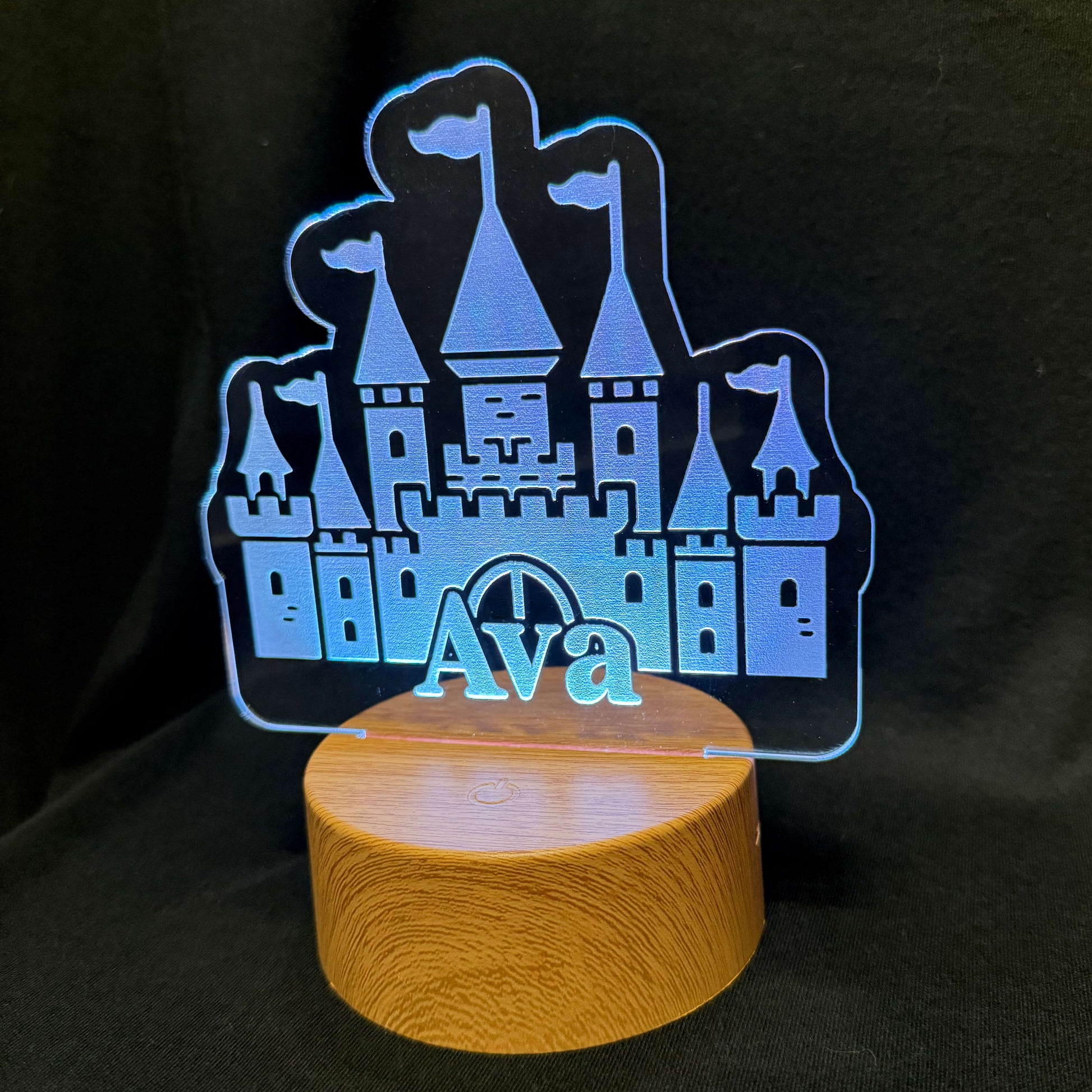 Castle-shaped night light with 'Ava' on a wooden base against a black background